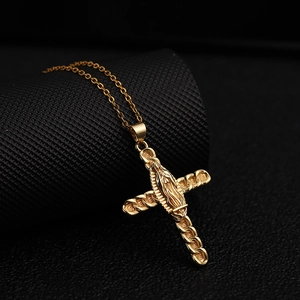 Close-up of gold cross pendant with Virgin Mary relief and textured chain details