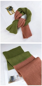 Detailed view of two-tone thick knit scarf in green and brick red winter textures