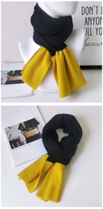 Detail of black and yellow bicolor knit scarf showing ribbed texture and two-tone design