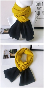 Detail of two-tone yellow and black ribbed knit scarf showing texture and drape on a mannequin