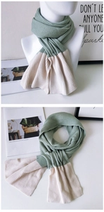 Detail of grey-green and beige color-block knitted scarf with soft wide-ribbed texture