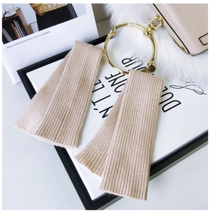 Close-up of soft ribbed knit arm warmers in beige featuring fine vertical textures
