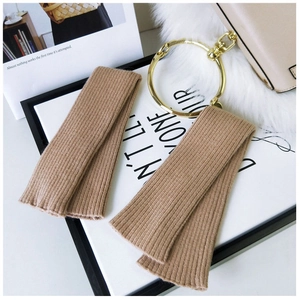 Close-up of camel knit arm warmers with ribbed texture on a cozy cream background