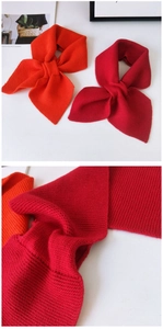 Detail of cross-knot knitted scarves in vibrant orange and deep red colors