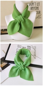 Detail view of grass green knitted scarf with crossover design and soft texture