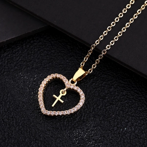 Collier cœur doré avec pendentif croix et cristaux micro-pavés sur fond noir texturé