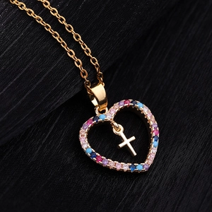 Détail du pendentif cœur doré avec zircons colorés et breloque en forme de croix