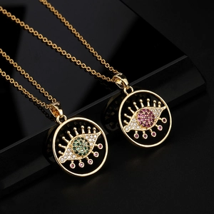 Gros plan de pendentifs mauvais œil dorés avec oxydes de zirconium verts et roses