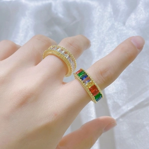 Close-up of gold adjustable rings with rainbow cubic zirconia on white silk fabric