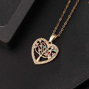 Collier cœur arbre de vie doré avec zircons colorés posé sur un fond noir élégant