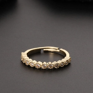 Detail of a golden adjustable ring with clear pavé zircon stones on a dark textured surface