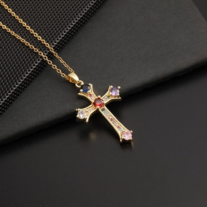Collier pendentif croix dorée hip hop avec zircons colorés sur texture noire