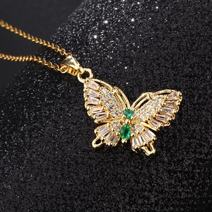 Détail macro du pendentif papillon doré orné de zircons blancs et d'accents verts