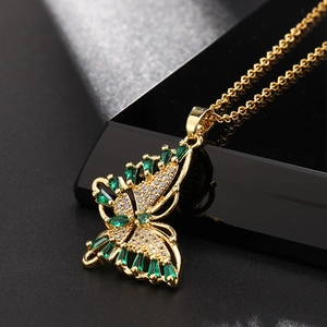 Vue macro d'un pendentif papillon doré avec des gemmes vertes et cristaux blancs