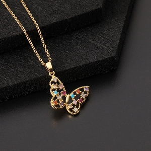 Détail du collier papillon doré serti de zircons multicolores sur un support texturé