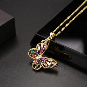 Vue détaillée du pendentif papillon doré orné de cristaux colorés sur un présentoir noir