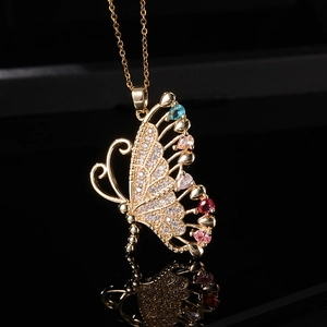 Vue macro du pendentif papillon doré avec gemmes colorées et micro-pavage de cristaux