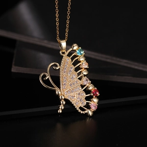 Macro de pendentif papillon doré serti de gemmes colorées sur fond noir texturé