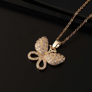 Macro d'un pendentif papillon doré avec pavé de zircons sur fond de cuir noir texturé