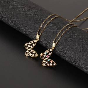 Détails des pendentifs papillon dorés avec zircone colorée sur support texturé noir