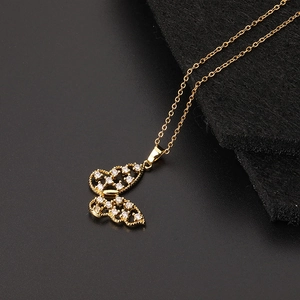 Gros plan du collier pendentif papillon doré orné de zircons sur un fond noir élégant