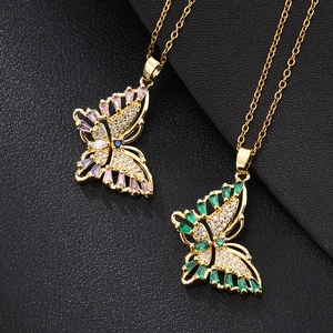 Détail de pendentifs papillon dorés sertis de zircons colorés sur fond en cuir noir texturé