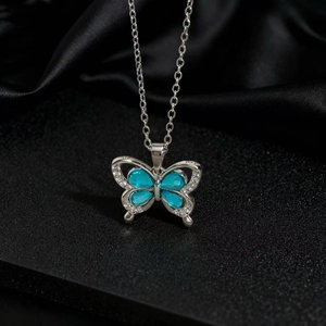 Détail du pendentif papillon argenté avec quatre pierres en zircon bleu clair serties