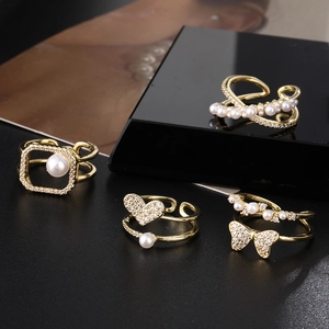 Modern gold plated four-piece ring set with pearls and zircons on black background
