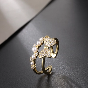 Detail of gold-plated bow ring with white pearls and sparkling zircon accents