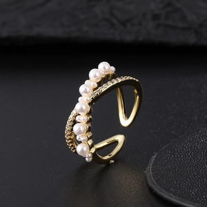 Macro shot of gold adjustable ring with pearls and pavé cubic zirconia on black background