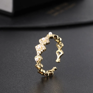 Macro detail of gold-plated geometric ring with inlaid zircon and white pearl
