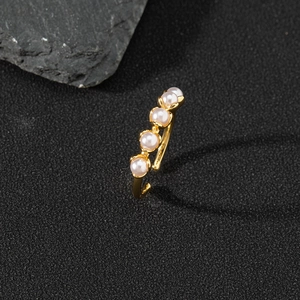 Detail of gold-plated pearl ring with zircon accents on a premium textured rock background