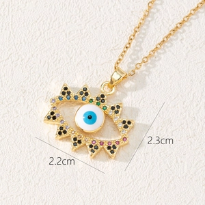 Macro detail of golden Evil Eye pendant showing colorful zircons and size dimensions
