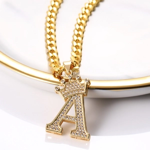 Détail du pendentif lettre A dorée avec couronne et zircons sur une chaîne cubaine
