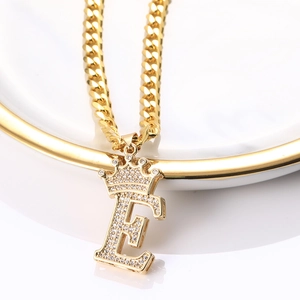 Vue détaillée du collier chaîne cubaine dorée avec pendentif lettre E à couronne sertie