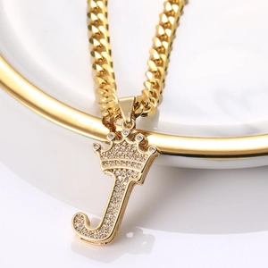 Détail du pendentif lettre J doré avec couronne et pierres de zircone serties