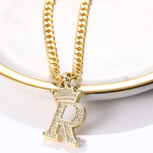 Détail macro du pendentif couronne lettre R doré avec zircons sur une chaîne cubaine