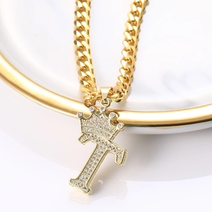 Vue macro du pendentif lettre T doré avec couronne sertie de zircons sur une chaîne cubaine