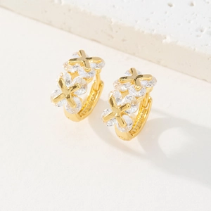 Détail de créoles plaquées or 18K avec zircons micro-incrustés et ornements en forme d'X