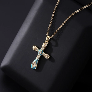 Dettaglio di un ciondolo a croce in oro con smalto blu e micro-pavé di zirconi cubici