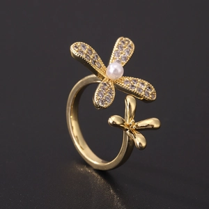 Macro detail of gold flower ring featuring cubic zirconia petals and a center white pearl