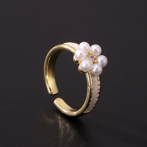 Detailed macro view of gold-plated ring with pearl flower and white enamel dripping oil