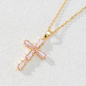 Elegant gold cross necklace with pink baguette zircon pendant on a textured white background