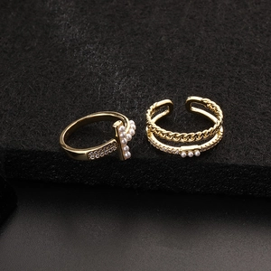 Detailed view of two gold-plated rings with micro-set zircons and elegant white pearls