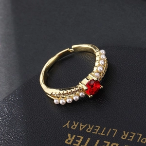 Macro detail of gold-plated ring featuring red gemstone and side pearl accents