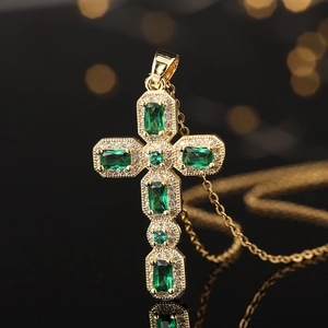 Détail d'un pendentif croix baroque en or avec pierres vert émeraude et micro zircons