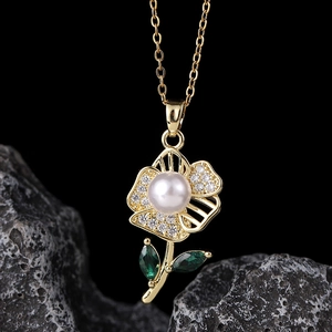 Macro detail of gold flower pendant necklace with white pearl and green zircon stones