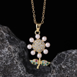 Detailed close-up of a gold flower pendant with white pearls and multicolored gemstones