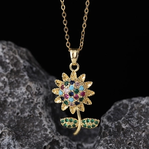 Close-up of golden sunflower pendant with multi-colored gemstones on a textured rock base