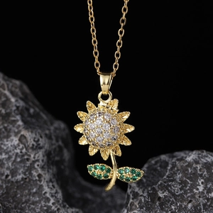 Detailed close-up of a sunflower pendant with green gemstones and white zircons